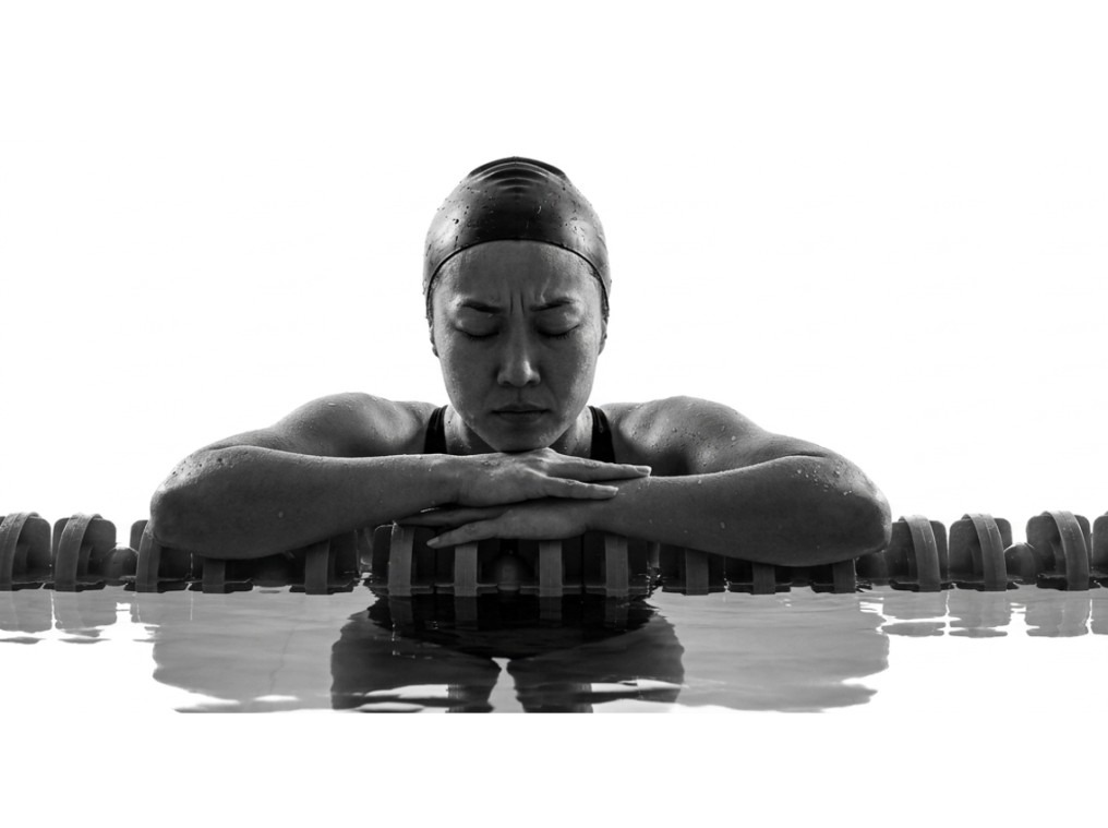 Age-group swimmer resting on a lane rope, eyes closed before the race